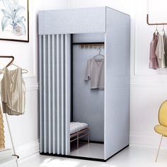 an open closet with clothes on hangers and a yellow chair in the foreground