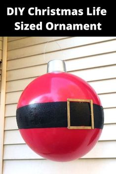 a red and black christmas ornament hanging from the side of a house