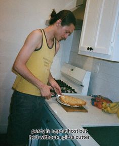 a man in a yellow tank top is cutting up food on a counter next to a stove