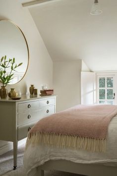 a bedroom with a bed, dresser and large round mirror in the middle of it