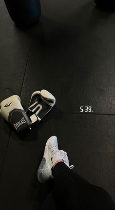 a pair of boxing gloves sitting on the ground next to a punching mitt and measuring tape