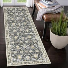 a large area rug in the middle of a living room with a chair and potted plant