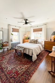 a bed room with a neatly made bed and a rug on top of the floor