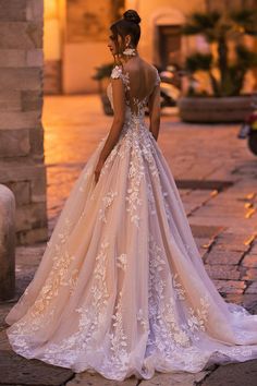 a woman in a wedding dress is standing on the street at night with her back to the camera