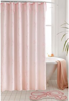 a bathroom with a pink shower curtain next to a white bath tub and rug on the floor