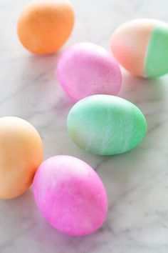 four different colored eggs on a marble surface