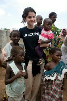 a group of people standing around each other with one holding a baby in her arms