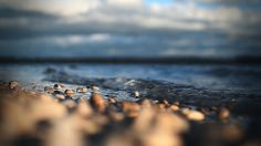 some rocks and sand on the beach under a cloudy sky