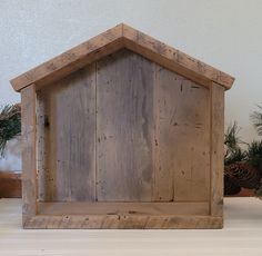 a wooden birdhouse sitting on top of a table next to pine cones and evergreens