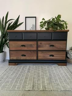 a large wooden dresser sitting next to a potted plant on top of a rug