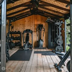 there are many exercise equipment in the gym area with wood walls and flooring on both sides