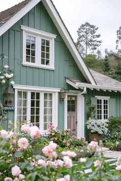 a green house with white windows and pink flowers