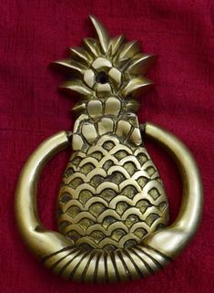 a brass pineapple door knocker on a red background