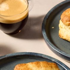 two blue plates with biscuits on them next to a cup of coffee and a drink