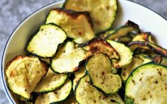 a white bowl filled with sliced zucchini on top of a table