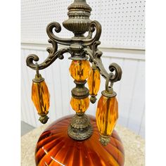 an orange glass lamp with three lights on it's sides and a metal base