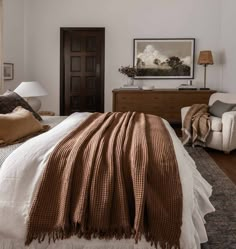 a bedroom with a bed, chair and pictures on the wall above it that is decorated in brown and white