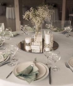 the table is set with plates, silverware and flowers