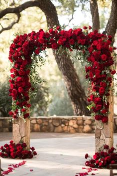 an outdoor ceremony with red roses and greenery