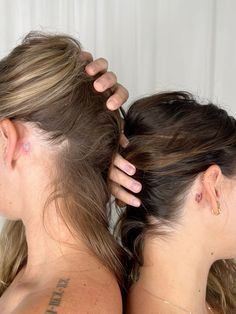 two women with tattoos on their backs are combing each other's long hair