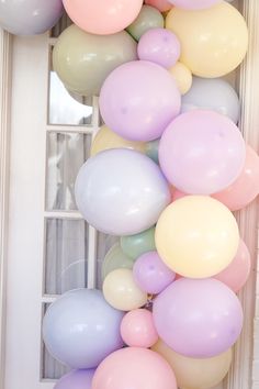 a bunch of balloons hanging from the side of a window sill in front of a white door