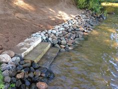 the rocks are lined up along the edge of the riverbank to create a wall