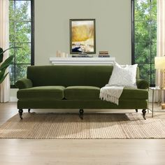 a living room with green couches and white pillows on top of the rugs