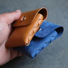 a hand holding a leather case on top of a blue piece of cloth in front of it