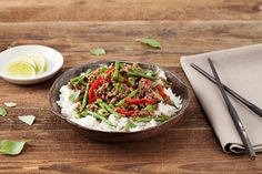 a bowl filled with rice, meat and veggies next to chopsticks