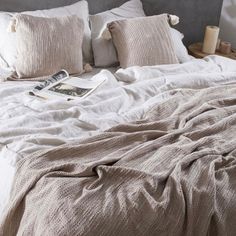 an unmade bed with white linens, pillows and blankets on top of it