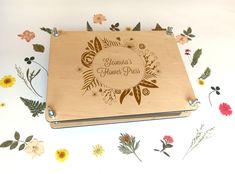 a personalized wooden notebook with flowers and leaves around it on a white tablecloth