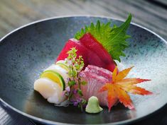 a plate that has some kind of sushi on it with leafy garnishes