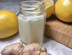 a ginger root next to a jar of liquid and two lemons