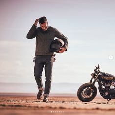 a man standing next to a motorcycle in the desert