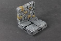 a miniature chair made out of silver and gold bricks on a black surface with the seat folded down