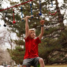 a young boy is playing with a toy in the park while holding onto a rope