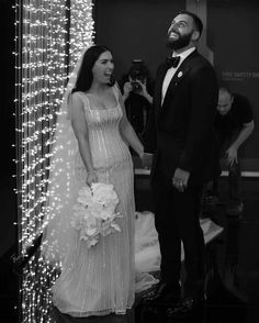 a man and woman standing next to each other in front of a wall with lights