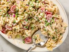 a plate full of pasta salad with peas and tomatoes