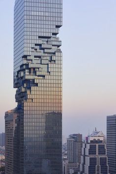 a tall building with lots of windows in the middle of it's face and some buildings behind it