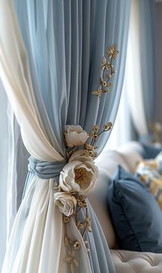 a bed with blue and white drapes on it's sides, along with flowers