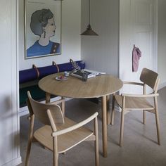 a wooden table with chairs around it and a painting on the wall in the background