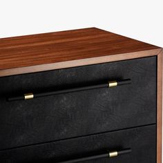 a black and wood dresser with two brass pulls on the bottom drawer, against a white background