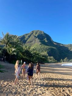 some people are walking on the beach near mountains