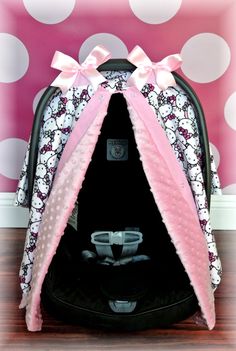 a hello kitty car seat cover with pink bows and polka dots on the wall behind it