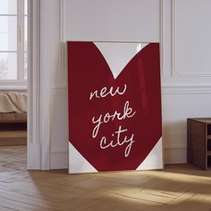 a red and white poster with the words new york city written on it next to a coffee table