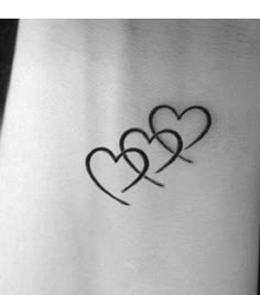 two hearts tattoo on the back of a woman's arm, with one heart in the middle