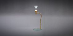 a glass and brass table lamp on a grey background