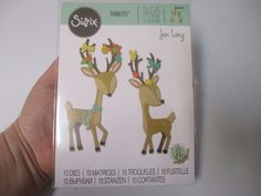 a hand holding up a box with two deer stickers on it