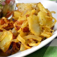 a white plate topped with cooked potatoes next to a small bowl of salsa on the side