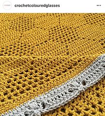 a yellow and white crocheted blanket on top of a table